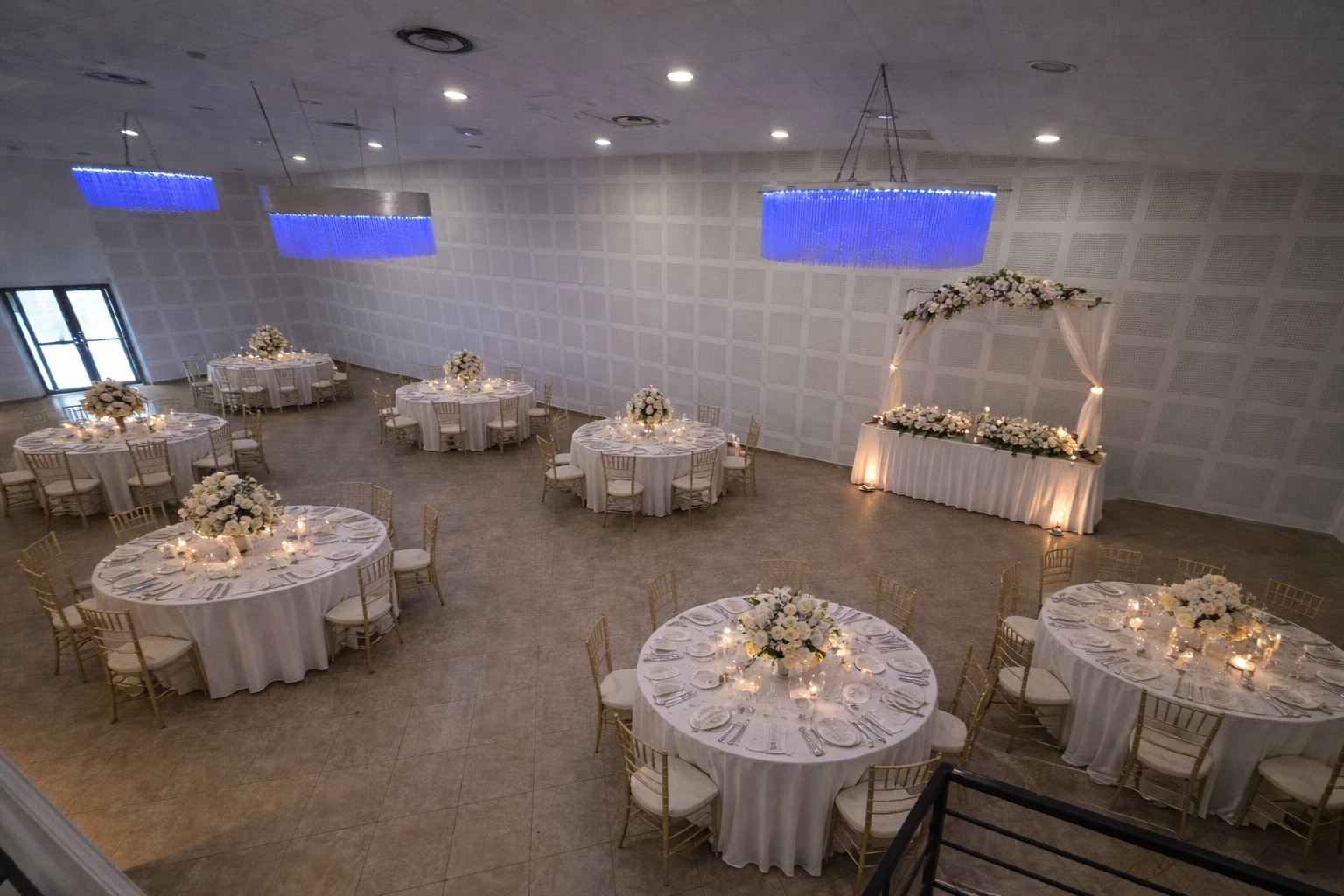 Tables rondes dressées avec arche florale et lustres bleus